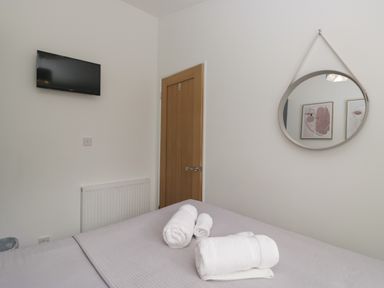 A bedroom with a television and towels on the bed at Ruskin Lodge, Langdale 16, White Cross Bay near Windermere