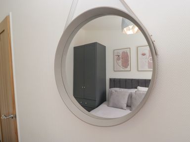 A reflection of a wardrobe and bed in a mirror at Ruskin Lodge, Langdale 16, White Cross Bay near Windermere