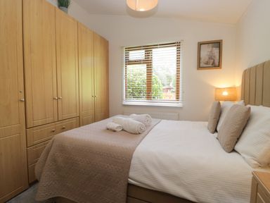 A bedroom with a double bed and wardrobe at Ruskin Lodge, Langdale 16, White Cross Bay near Windermere