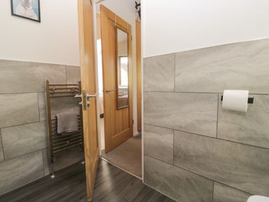 A bathroom with a towel rack and door at Ruskin Lodge, Langdale 16, White Cross Bay near Windermere