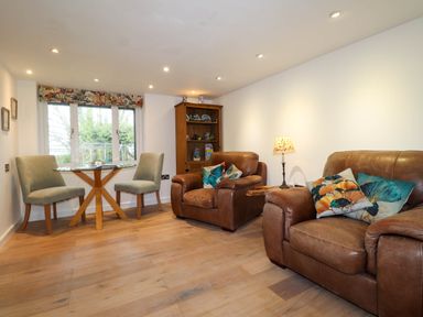 A living room with two leather armchairs and a small dining table with two chairs at The Studio at Dan y Garn in Newport Pembrokeshire