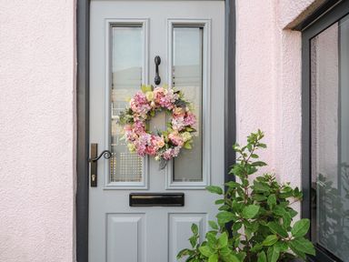 A front door with a floral wreath and a plant beside it at Moon's Cottage in Fowey