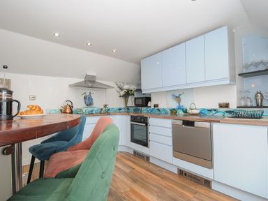 A kitchen with colorful chairs and blue cabinets at Moons Cottage in Fowey