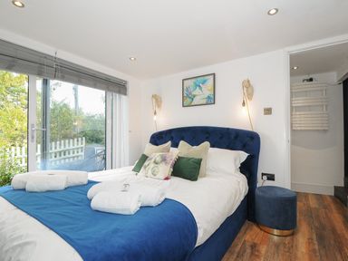 A bedroom with a blue bed and pillows next to sliding glass doors at Moon's Cottage in Fowey