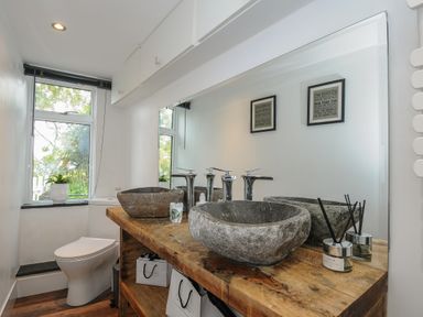 A bathroom with a wooden countertop and stone sinks next to a window with a toilet at Moons Cottage in Fowey
