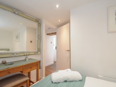 A bedroom with a wooden desk and a large mirror above it at Moons Cottage in Fowey