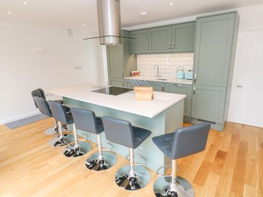 A kitchen with a large island and five bar stools at James Place in Falmouth