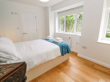 A bedroom with a bed covered in white linens and a blue blanket and towels on top by a window at James Place in Falmouth