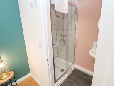 A shower with glass doors and tiled walls in a bathroom next to a sink at James Place in Falmouth