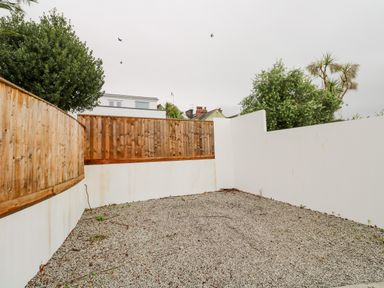 An outdoor area with gravel ground white and wooden fences and some trees at James' Place in Falmouth
