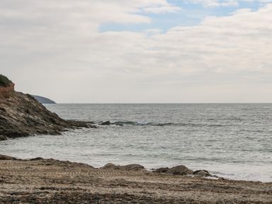 A rocky beach with ocean waves and a cloudy sky at James Place in Falmouth