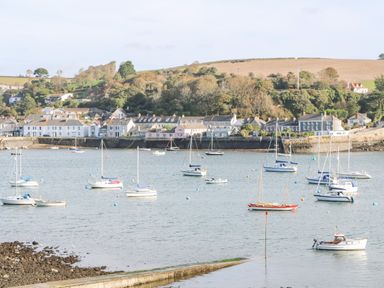A harbor with boats on the water and houses along the shoreline at James Place in Falmouth