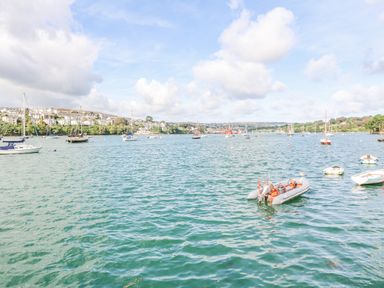 A body of water with multiple boats and sailboats near a town and hills at James Place in Falmouth