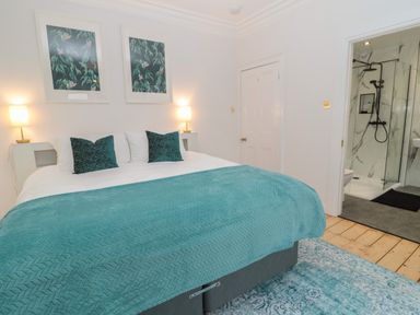 A bedroom with a double bed two bedside lamps and an open door leading to a bathroom at St Aidans in Alnwick