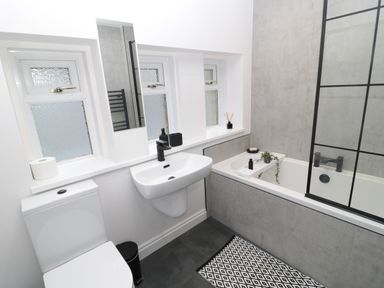 A bathroom with a toilet sink bathtub and small windows at St Aidans in Alnwick