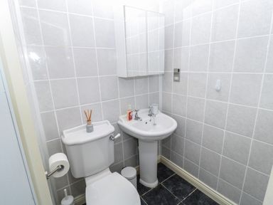 A small bathroom with a toilet sink mirror cabinet and tiled walls at St Aidans in Alnwick