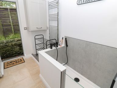 A bathroom with a shower area a towel rack a storage cabinet and a door leading outside at St Aidans Alnwick