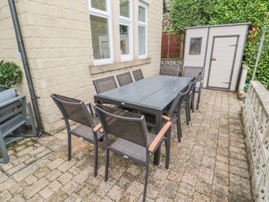 An outdoor patio area with a dining table surrounded by chairs and a storage shed at St Aidans in Alnwick