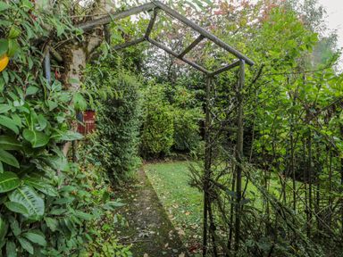 A garden pathway with greenery and a metal archway at St Aidans in Alnwick