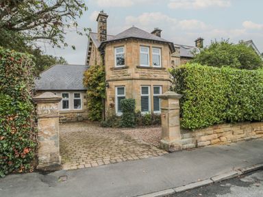 Stone house with two pillars at the driveway entrance and bushes on the sides at St Aidans in Alnwick