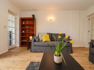 A living room with a gray sofa yellow cushions a wooden bookshelf and a plant on a black coffee table at Harran Annex in Peopleton