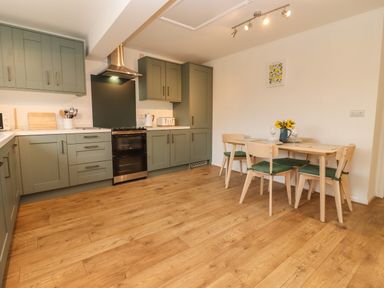 A kitchen with green cabinets a dining table with four chairs and wooden flooring at Harran Annex in Peopleton