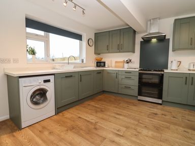 A kitchen with green cabinets a washing machine a microwave and a stove at Harran Annex in Peopleton