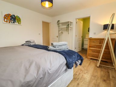 A bedroom with a bed and folded towels on it next to a wooden dresser a standing mirror and an open closet at Harran Annex in Peopleton