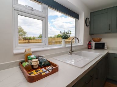 A kitchen countertop with a sink a tray with food items a microwave and a window above the sink at Harran Annex in Peopleton