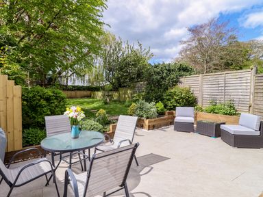 An outdoor patio with a glass table and chairs and garden furniture with plants and trees at Harran Annex in Peopleton