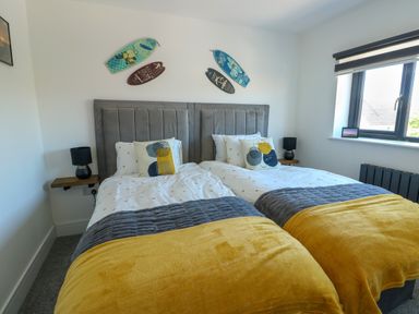 A bedroom with two beds and wall art at Iscoed Rhosneigr