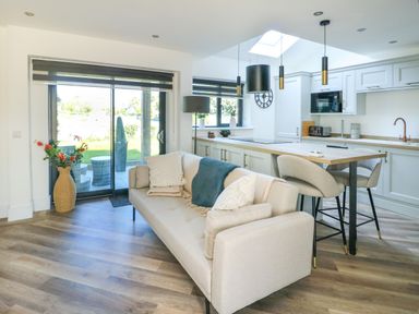 A living room and kitchen with a sofa and dining table at Iscoed Rhosneigr