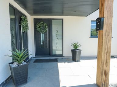 An entrance with a black door and planters at Iscoed Rhosneigr