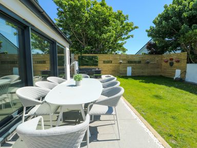 An outdoor dining area with a table and chairs at Iscoed Rhosneigr