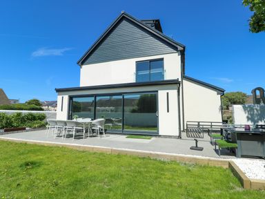 A house with a patio and outdoor seating at Iscoed Rhosneigr