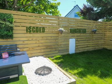 A garden with a fenced area and a table at Iscoed in Rhosneigr