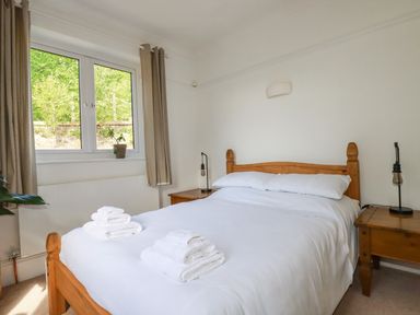 A bedroom with a wooden bed and bedside tables with lamps at Penang in St Austell