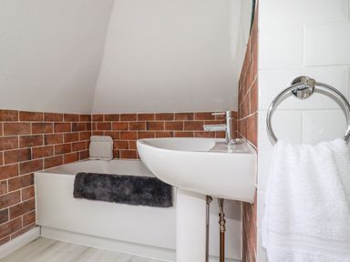 A bathroom with a bathtub a sink and a towel ring with a white towel at Penang in St Austell