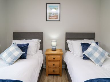 A bedroom with two single beds and a wooden nightstand with a lamp at Ashdale in Bwlch-y-sarnau near Rhayader