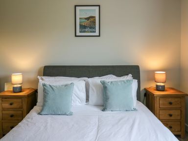 A bedroom with a bed two pillows two bedside tables with lamps and a framed picture on the wall at Ashdale in Bwlch-y-sarnau near Rhayader