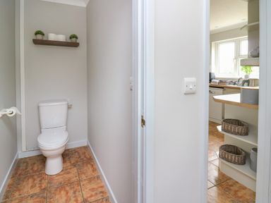 A toilet with a shelf above holding plants and candles next to a kitchen with shelves and baskets at Ashdale Bwlch-y-sarnau near Rhayader