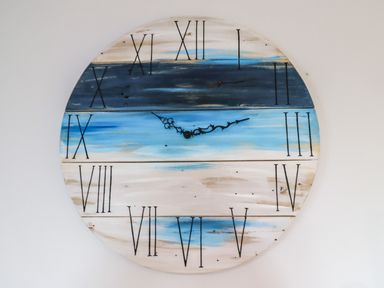 A round wall clock with roman numerals and blue and white painted wooden slats at 2A The Anchorage in Beadnell