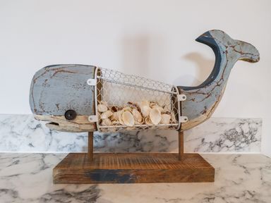A decorative wooden whale with a wire mesh body filled with seashells on a marble surface at 2A The Anchorage in Beadnell