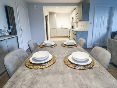 A dining table set with plates and bowls in a kitchen and dining room area at 2A The Anchorage in Beadnell