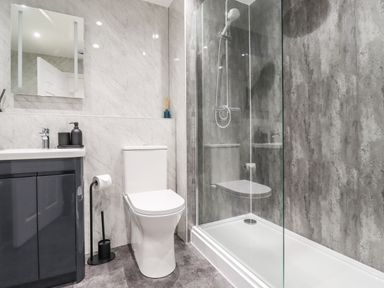 A bathroom with a toilet sink with cabinet and a glass shower at 2A The Anchorage in Beadnell