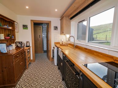A kitchen with wooden countertops a sink stove a wooden cabinet and patterned tile floor at The Croft in Newtown-Crommelin near Cloughmills