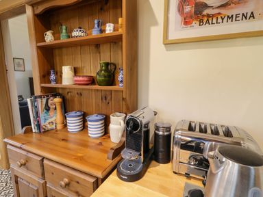 A kitchen counter with a coffee machine toaster kettle and wooden shelving with ceramics and cookbooks at The Croft in Newtown-Crommelin near Cloughmills
