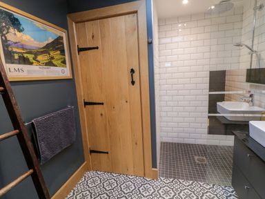 A bathroom with patterned tile floor wooden door white subway tile shower area and a framed picture on the wall at The Croft in Newtown-Crommelin near Cloughmills