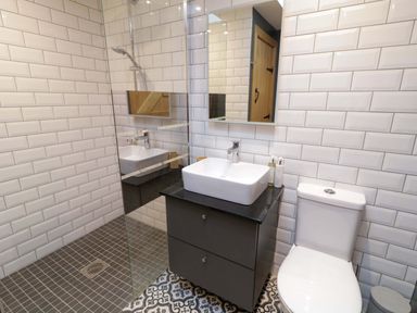 A bathroom with a sink on a black vanity and a toilet near a glass shower at The Croft in Newtown-Crommelin near Cloughmills