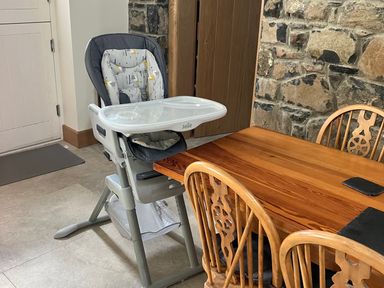 A dining area with a wooden table surrounded by wooden chairs and a baby high chair at The Croft in Newtown-Crommelin near Cloughmills